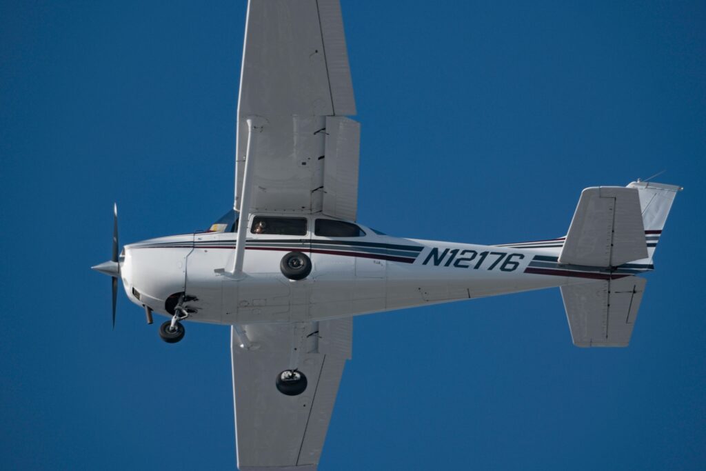 High-angle view of a private airplane soaring in a clear blue sky, showcasing aviation and freedom.